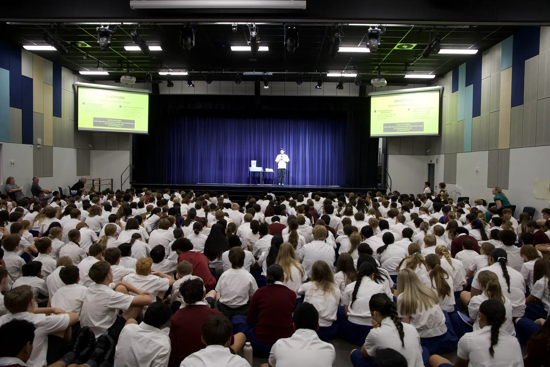 Cooper Chapman presenting to a full high school auditorium
