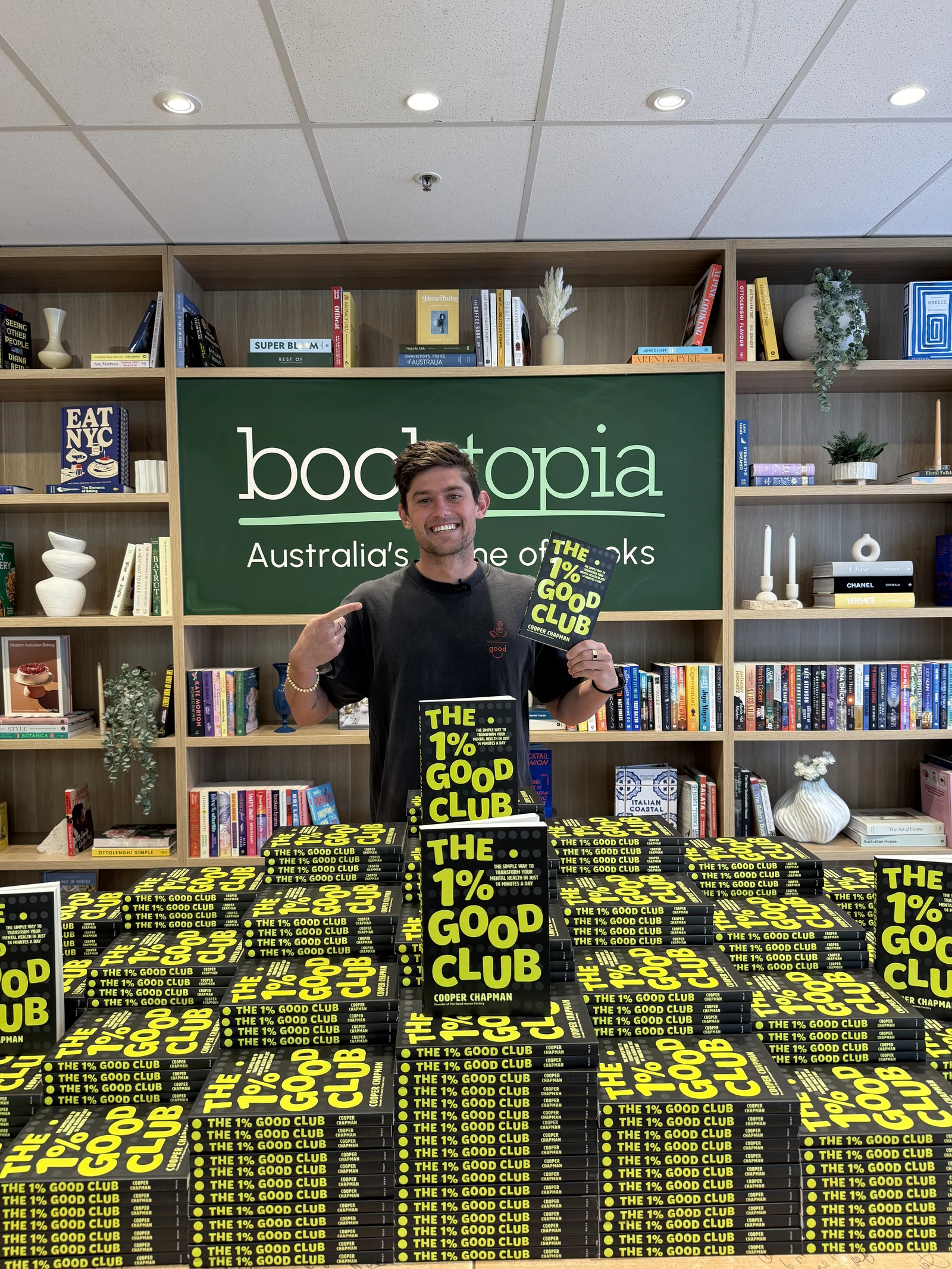 Cooper Chapman at Booktopia with stacks of The 1% Good Club